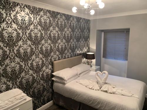 a bedroom with a bed and a wall with wallpaper at The Snug Garden Apartment in Llandudno