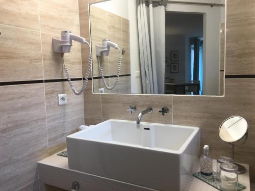 een badkamer met een witte wastafel en een spiegel bij Couette et Café in Montpellier