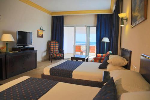 a hotel room with two beds and a television at Lahami Bay Resort in Abū Ghuşūn