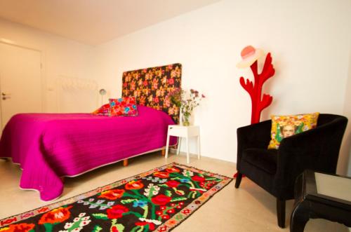 a bedroom with a pink bed and a chair at Mi Casa Tu Casa - Dead Sea in Vered Yeriho