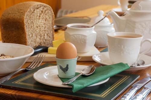 a table with a egg on a plate and cups of coffee at Rye Hill Farm in Hexham