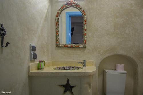 a bathroom with a sink and a mirror and a toilet at Puerta Azul in Chefchaouene