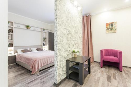 a bedroom with a bed and a pink chair at Apartment on Oktyabrskaya in Kaliningrad
