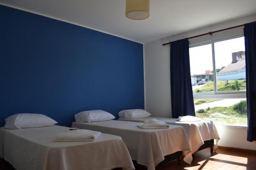 two beds in a room with a blue wall at Apart Porto del Sol by CPH in Villa Carlos Paz