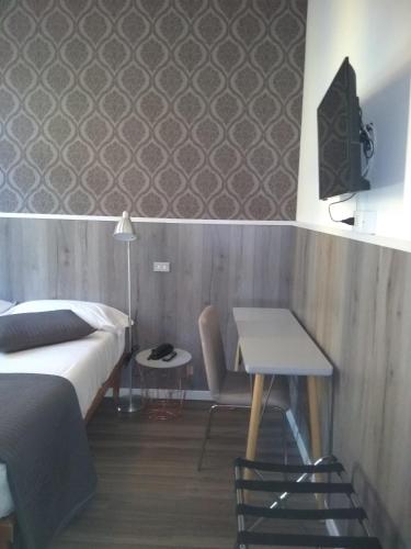 a bedroom with a bed and a table and a desk at Hotel Malta in Milan