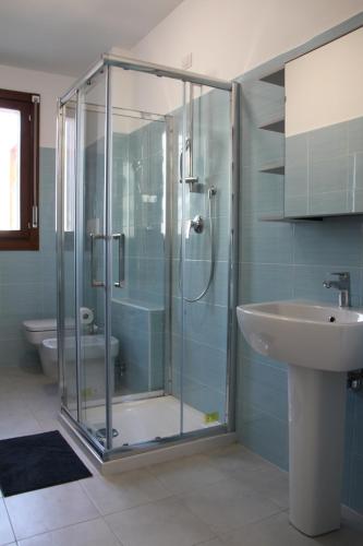 W łazience znajduje się szklana kabina prysznicowa i umywalka. w obiekcie Luxory Suites w mieście Sesto San Giovanni