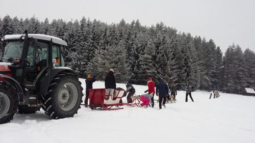 a group of people standing in the snow next to a tractor at Agroturystyka na Słonecznej Orawie u Dzikich in Jabłonka