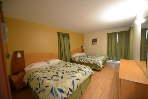 a hotel room with two beds and green curtains at Condos-Hotels Natakam, Communauté Autochtone in Les Escoumins