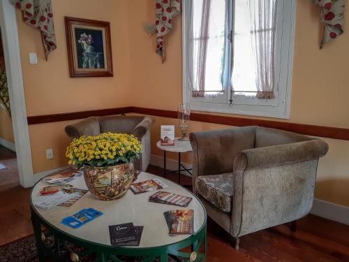 sala de estar con 2 sillas y mesa con flores en Pousada Palacio de Cristal en Petrópolis