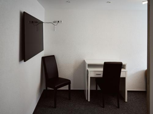 2 stoelen en een bureau in een kamer met een muur bij Boardinghouse Apart-Hotel in Oberkochen