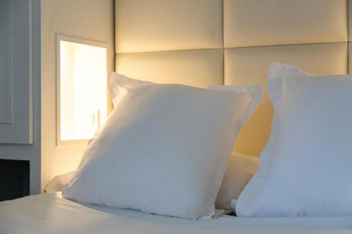 a bed with white pillows on it with a window at The Originals City, Hôtel Lecourbe, Paris Tour Eiffel in Paris
