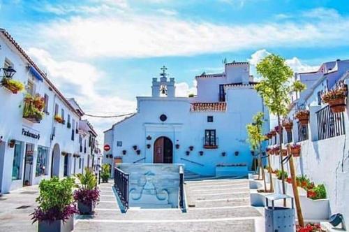 a white building with a clock tower in a street at La casa del barrio in Mijas