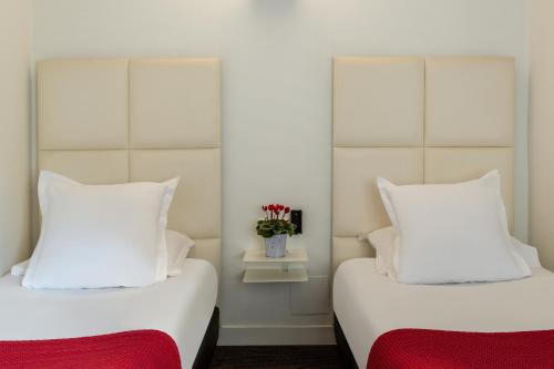 two beds with white pillows and a vase with flowers at The Originals City, Hôtel Lecourbe, Paris Tour Eiffel in Paris