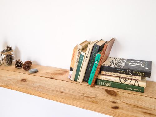 a pile of books sitting on a wooden shelf at Downtown Forest Hostel & Camping in Vilnius