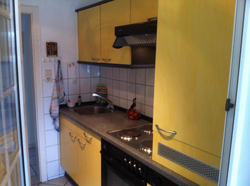 a kitchen with yellow cabinets and a sink at Haus Pamela in Neuharlingersiel