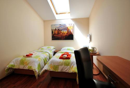 a bedroom with two beds and a desk and a painting at AL-Tour in Gdynia