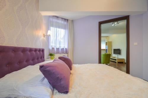 a bedroom with a bed with a purple headboard and a mirror at Apartament Krupówki 4 os CENTRUM in Zakopane