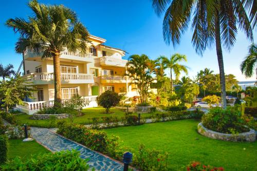 a large building with palm trees and a yard at Las Palmeras by Graziano in Boca Chica