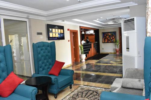 a lobby with blue chairs and a table at Qualibest Grand Hotels in Abuja