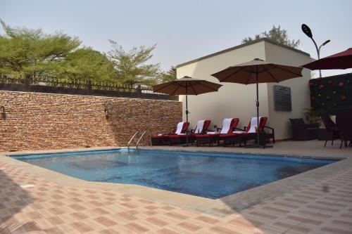a swimming pool with chairs and umbrellas next to a building at Qualibest Grand Hotels in Abuja