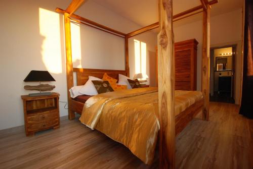 - une chambre avec un grand lit et un cadre en bois dans l'établissement Le Mas Des Sorcières - Maison d'hôtes, à Valréas