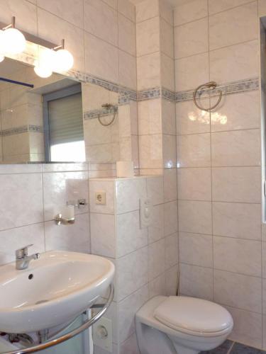 a white bathroom with a sink and a toilet at Ferienwohnung zum Yachthafen in Waren