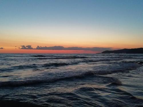 a sunset on the beach with the ocean at Tana delle Sirene Cilento Coast Acciaroli Sea Pollica in Acciaroli