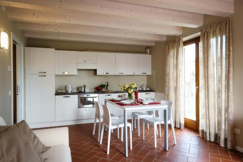 a kitchen with white cabinets and a table and chairs at Belvivere Suites in Sona