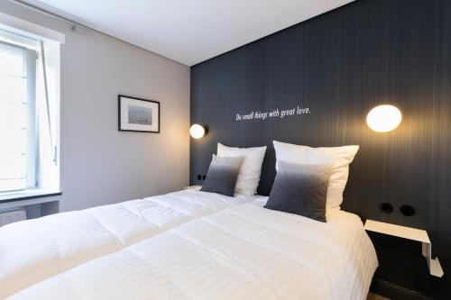 a bedroom with a large white bed with a black wall at Hotel-Restaurant Beim Schlass in Wiltz