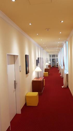 a hallway with a row of chairs and a red carpet at Schlosshotel Domäne Walberberg in Bornheim