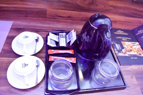 a black vase sitting on a table with plates and cups at Qualibest Grand Hotels in Abuja