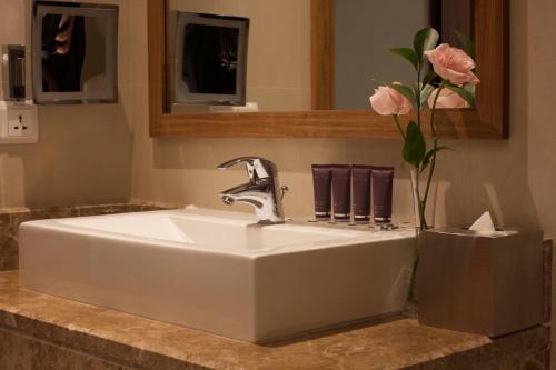 a sink in a bathroom with a vase of pink roses at Somewhere Hotel Al Ahsa in Al Hofuf