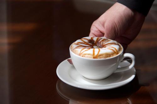 a person holding a cup of coffee on a table at Somewhere Hotel Al Ahsa in Al Hofuf