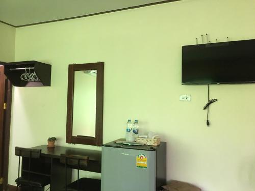 a room with a refrigerator and a table and a mirror at Baan Mai Muang Nan in Nan