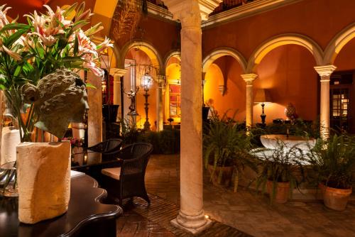 a lobby with tables and plants in a building at Hotel Casa Del Poeta in Seville