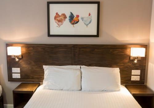a bed with a wooden headboard with two lamps and chickens on the wall at Starling Cloud in Aberystwyth