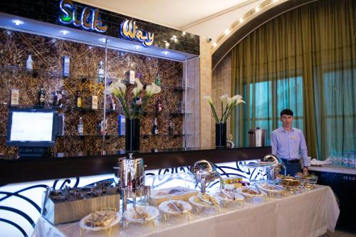 a man standing behind a buffet table in a restaurant at Hotel Zhibek Zholy in Shymkent