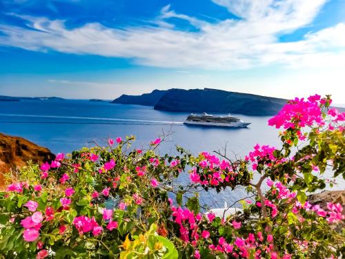 a cruise ship in the water with pink flowers at Marizan Caves & Villas in Oia