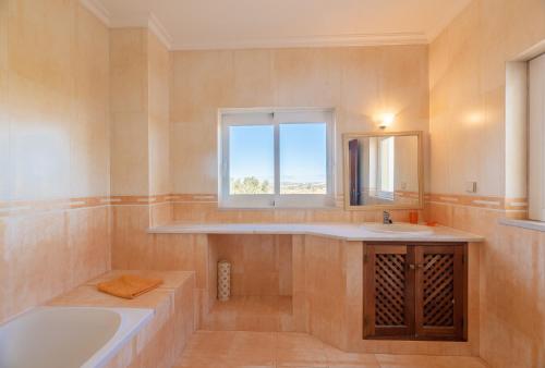 a bathroom with a tub and a sink and a window at Villa Agua by Gabi Miguel in Albufeira