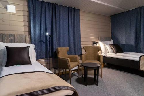 a hotel room with two beds and a table and chairs at Vollan Gjestestue in Nordkjosbotn
