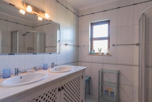 uma casa de banho com 2 lavatórios, um espelho e um chuveiro em Villa Andrea by Gabi Miguel em Albufeira