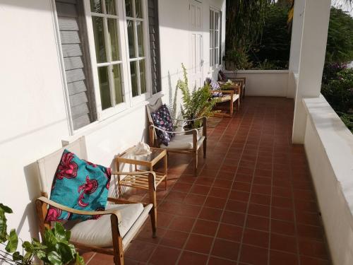a row of chairs on the porch of a house at Green Roof Inn in Carriacou