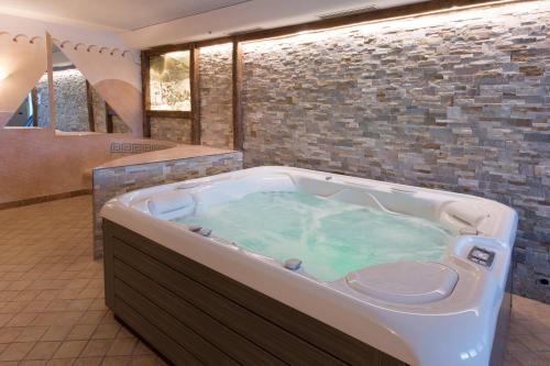 a hot tub in a bathroom with a stone wall at Hotel Föhrenhof in Natz-Schabs