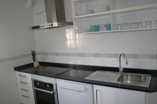 a white kitchen with a sink and a stove at Fantastic, 100 meters from the beach in Can Picafort