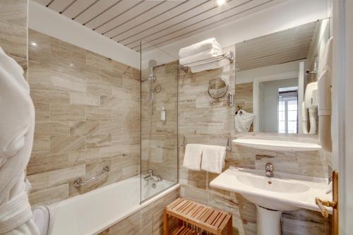 La salle de bains est pourvue d'une baignoire, d'un lavabo et d'une douche. dans l'établissement Hôtel Sèvres Saint Germain, à Paris