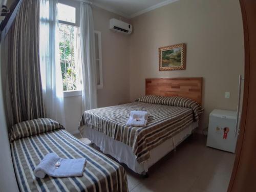 um quarto de hotel com duas camas e uma janela em Pousada Palacio de Cristal em Petrópolis