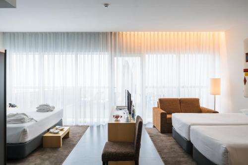 a hotel room with two beds and a chair at Boticas Hotel Art & SPA in Boticas