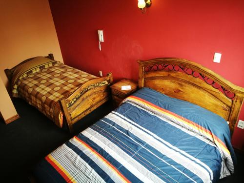 a bedroom with two beds and a red wall at Bolivian Heights Hostel in La Paz