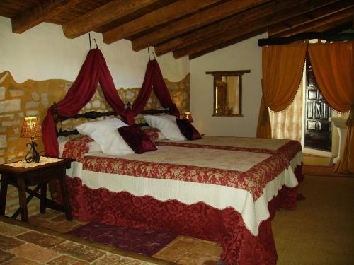 a bedroom with a large bed with red curtains at Hotel Boutique Condes Fúcares in Almadén