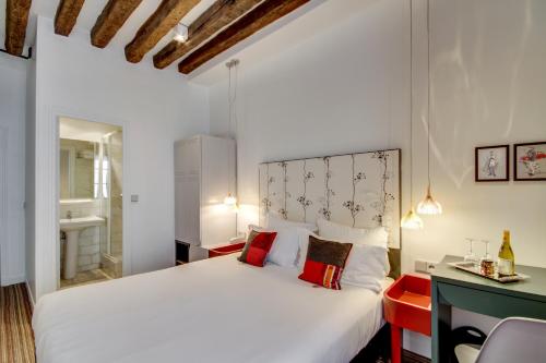 a bedroom with a large white bed with red pillows at Hôtel Sèvres Saint Germain in Paris